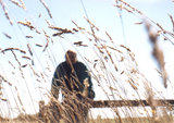 A blurry David sits on a fence behind in-focus grass