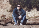 Dave sitting on a log on the beach